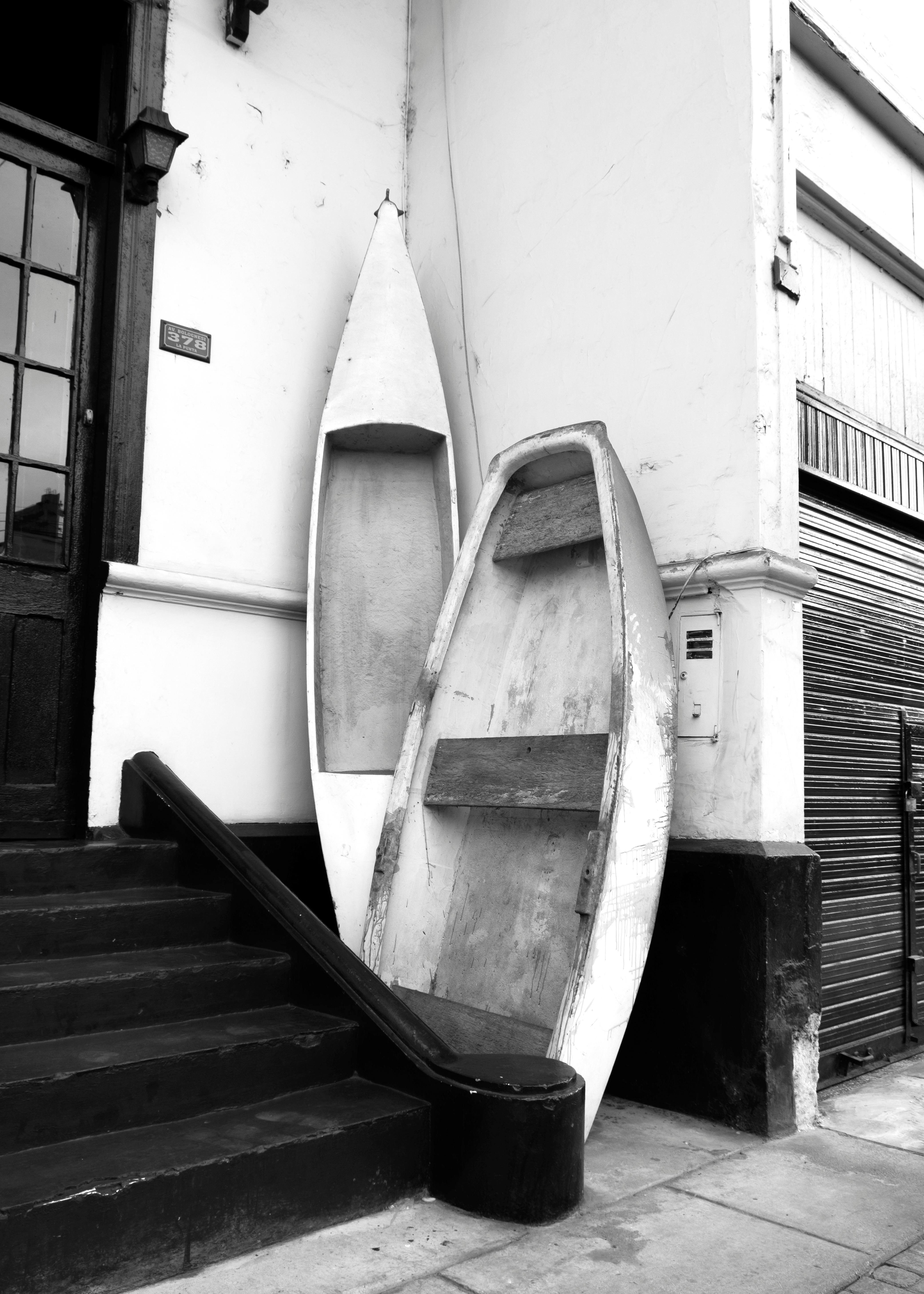Black and white image of wooden boats leaning on a vintage building in La Punta, Callao, Perú.