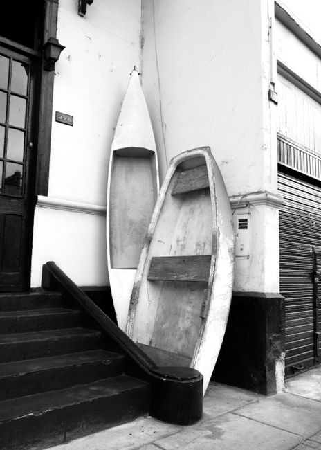 Black and white image of wooden boats leaning on a vintage building in La Punta, Callao, Perú.