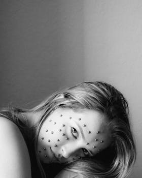 Black and white portrait featuring a woman with unique dot pattern makeup and long hair.