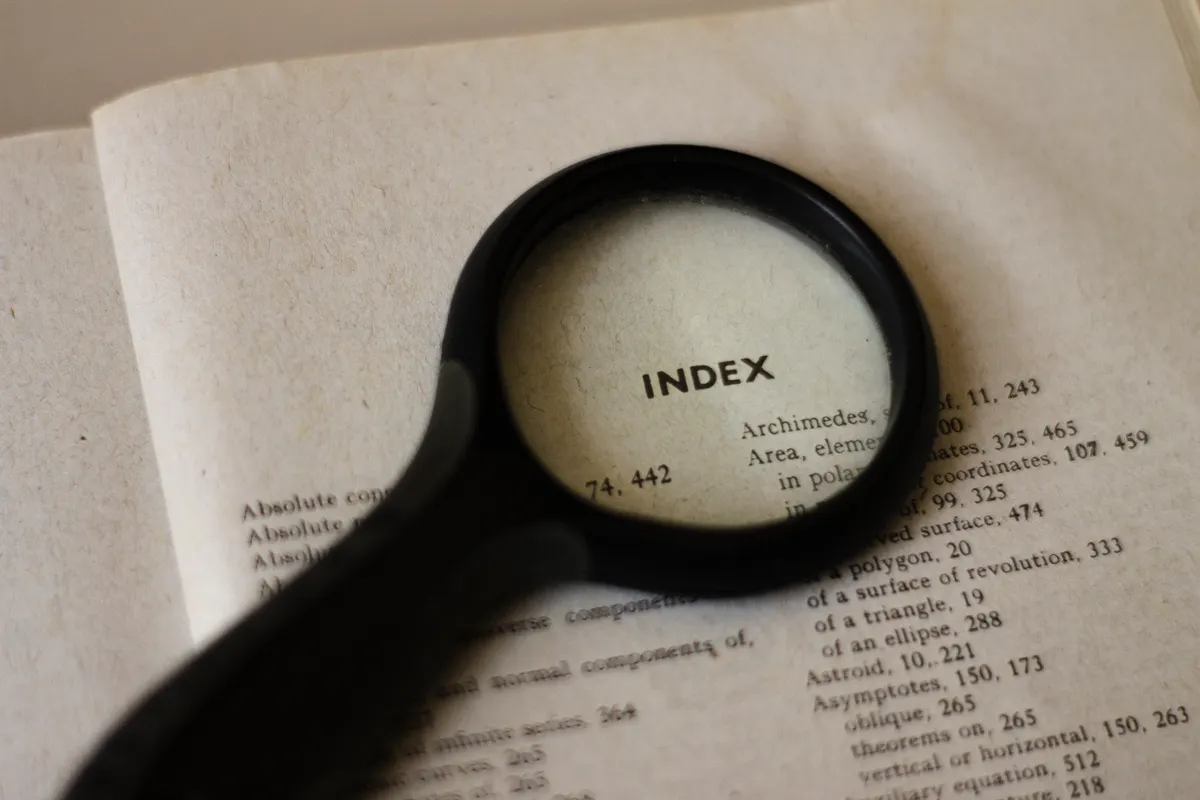 Magnifying glass over a book index, representing search engine guidelines and seo.