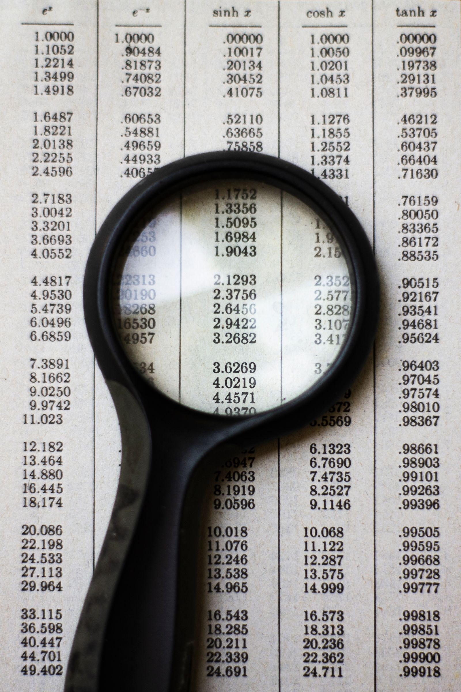 Magnifying glass held over a printed table of numbers