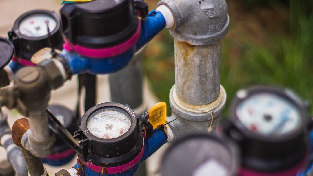 A water meter and pressure gauges on an outdoor pipe run