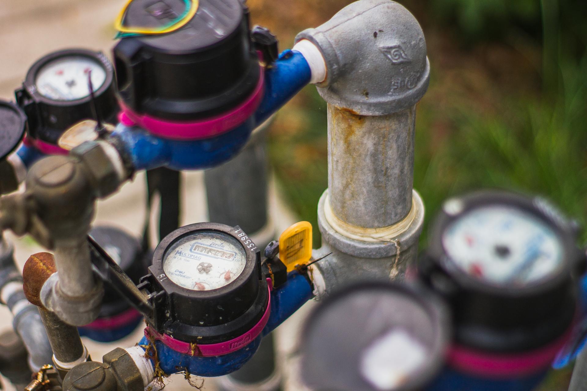 Detailed image of industrial water pressure gauges and pipes in an outdoor setting.