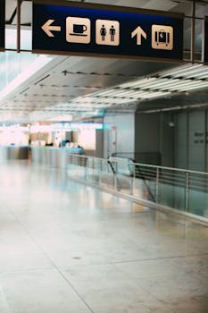 Illuminated airport corridor with directional signage for amenities and services.
