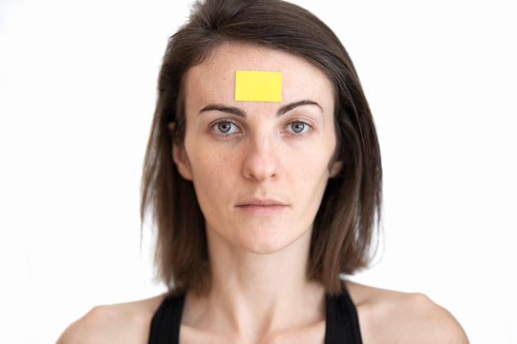 A Woman With Yellow Sticker On Her Forehead