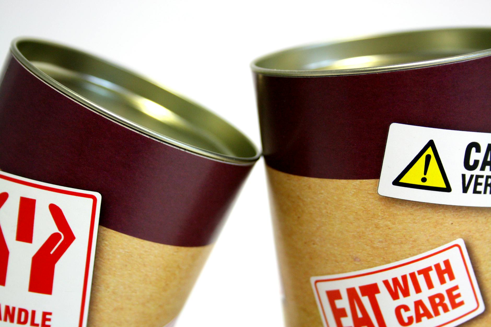 Close-up view of warning labels on canned food containers indicating caution and safety.