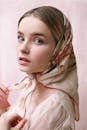 Unemotional young female in casual clothing with headscarf looking at camera in bright room