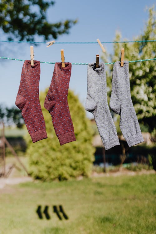 Multicolored socks drying on rope with clothespins in garden
