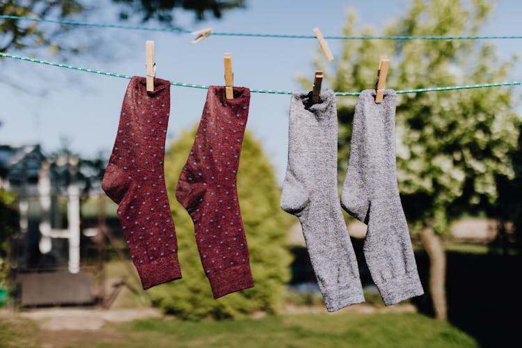 Multicolored Socks Drying On Rope With Clothespins In Open Air