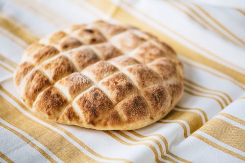 Free From above of tasty homemade bread loaf on table with fabric linen tablecloth Stock Photo