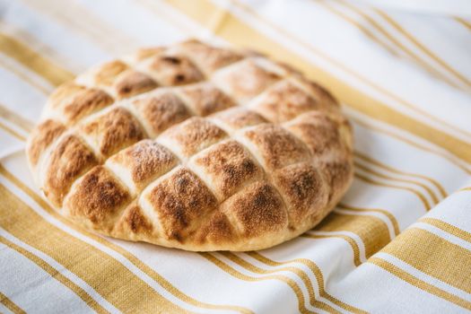 From above of tasty homemade bread loaf on table with fabric linen tablecloth