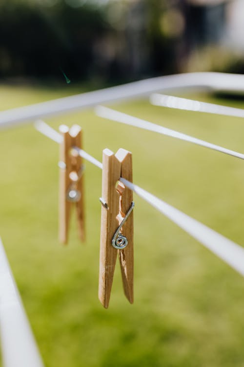 Metall folding clotheshorse placed on green lawn in garden with wooden clothespins on sunny day