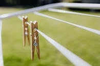 Composition of wooden clothespins hanging on collapsible clotheshorse placed on green lawn in garden on sunny day