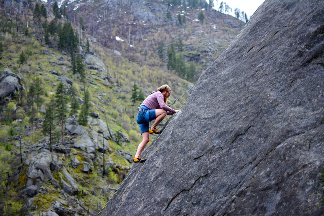 Free Man Climbing on Rock Mountain Stock Photo