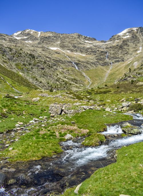 Free Majestic view of rocky valley with mountains and clean mountainous stream in calm highland valley with colorful green grass and blue sky in sunny day Stock Photo