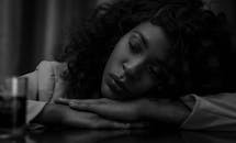 一位非裔美国妇女在餐桌旁内省的黑白肖像