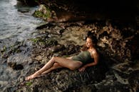 一个穿着泳装的宁静女人在日落时分在海边的岩石岸上放松