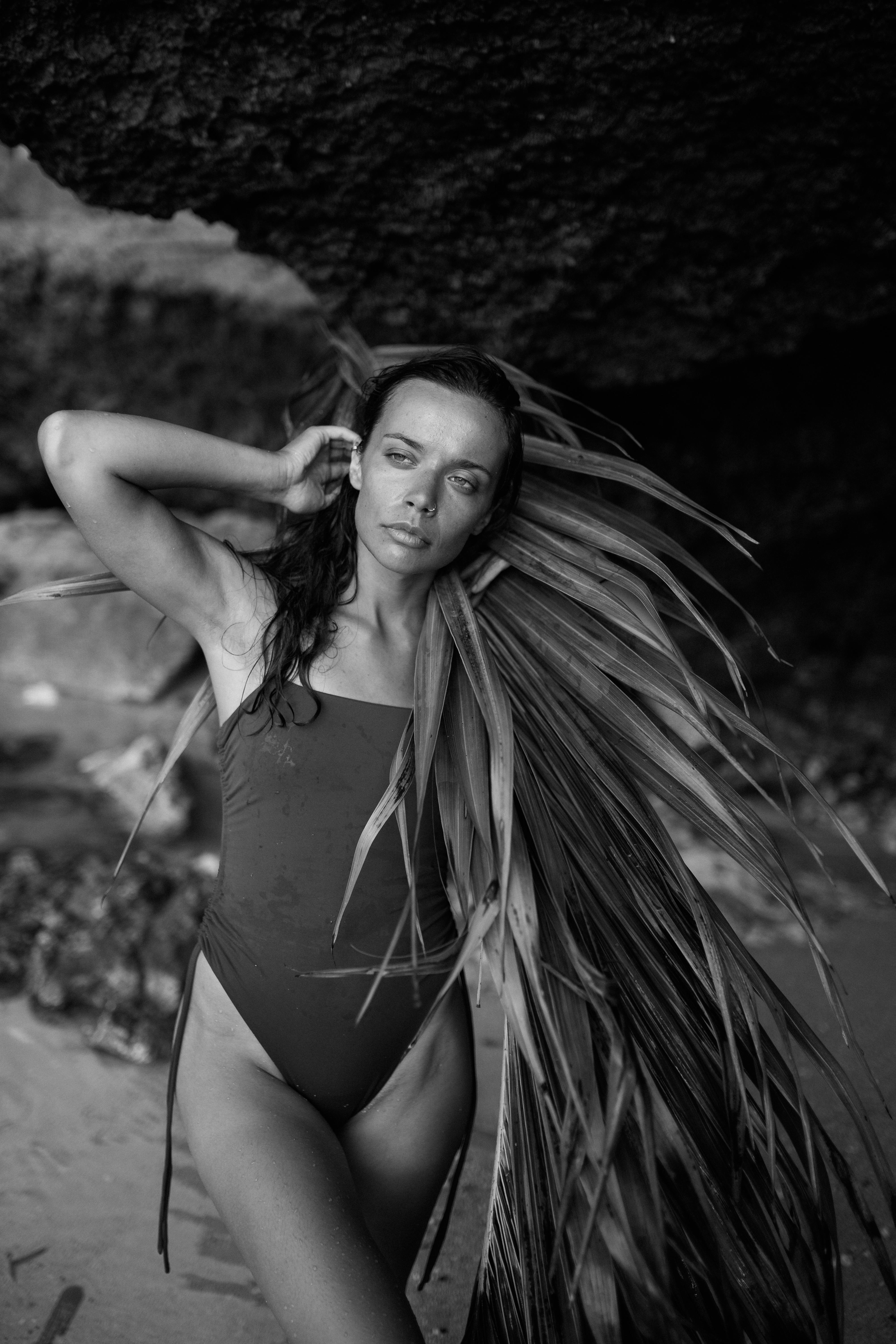 Young woman in bathing suit standing near rock on beach · Free Stock Photo