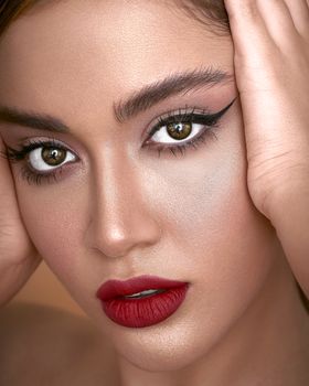 Close-up portrait of a woman with striking makeup and healthy skin, showcasing red lips.