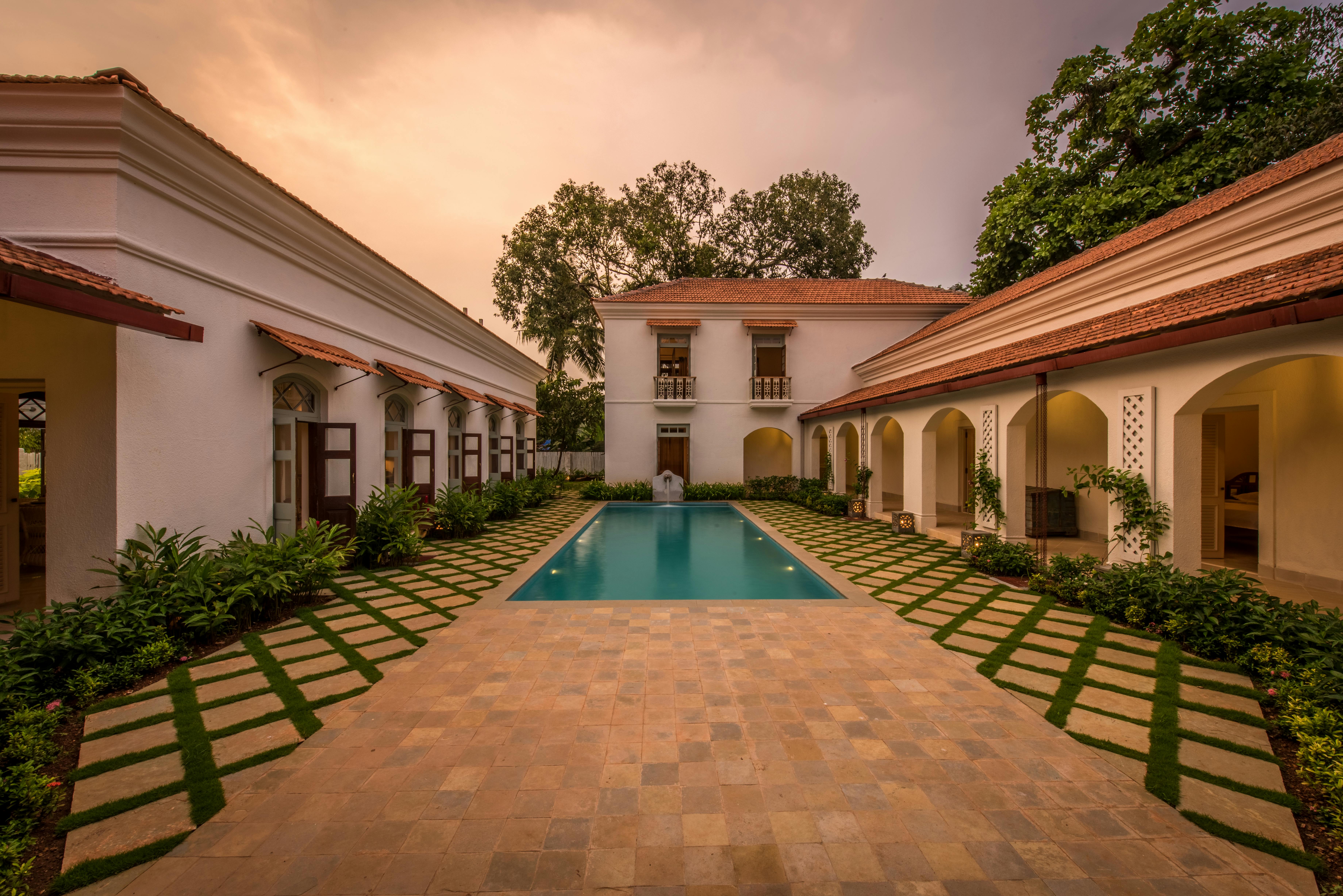 Beautiful villa with a central pool surrounded by lush greens, captured at sunset. - Photo by Souranshi Fashion and  Lifestyle Magazine on Pexels