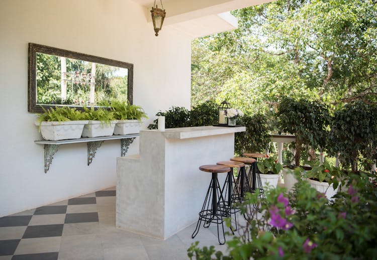 A Patio With Bar Counter And Stools Around Trees And Plants