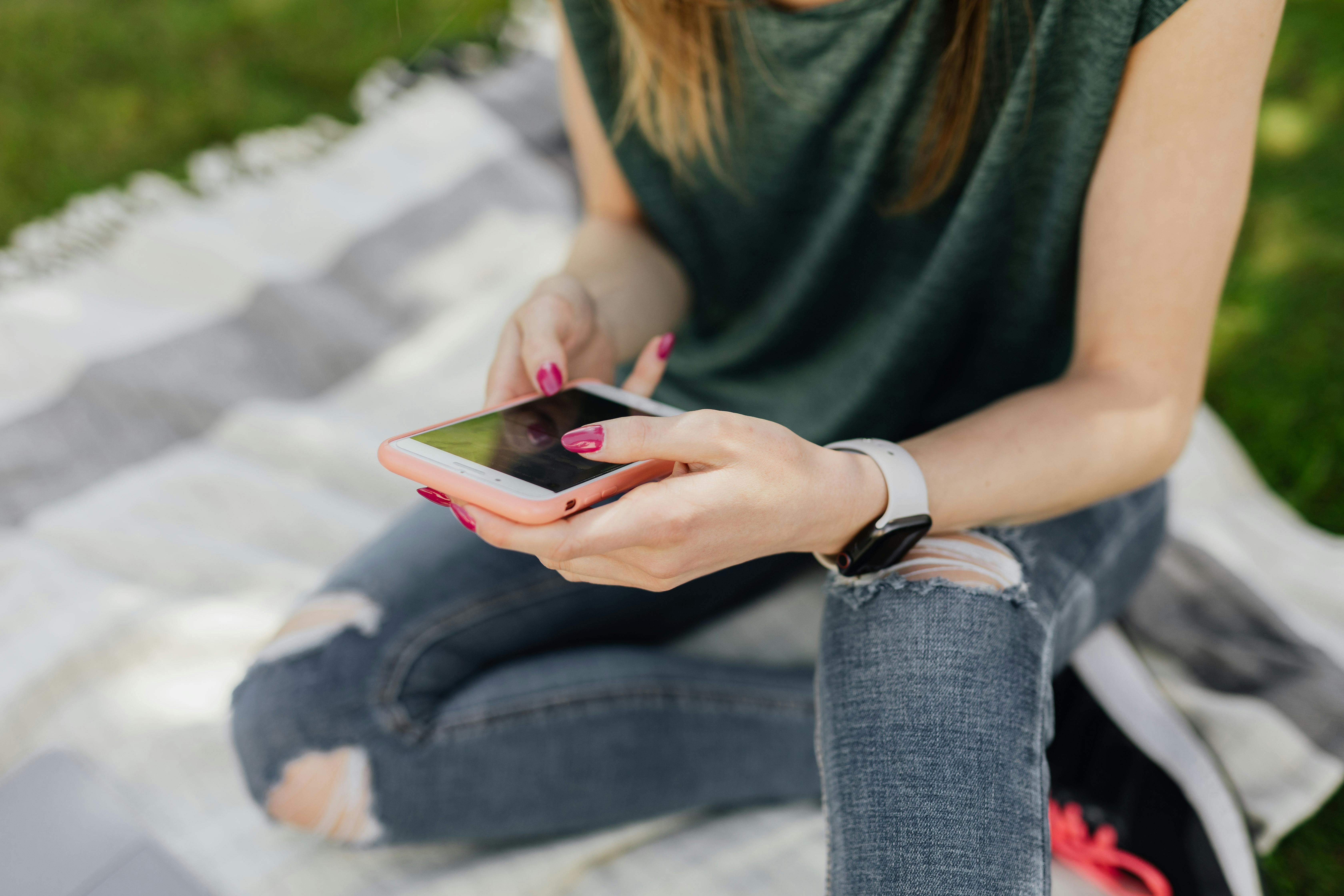 crop lady using mobile while sitting in park