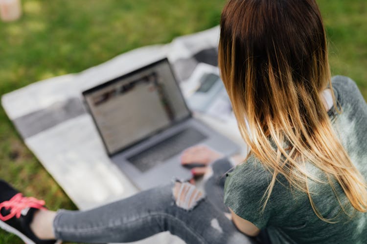 Youngster Surfing Net On Laptop While Relaxing In Park