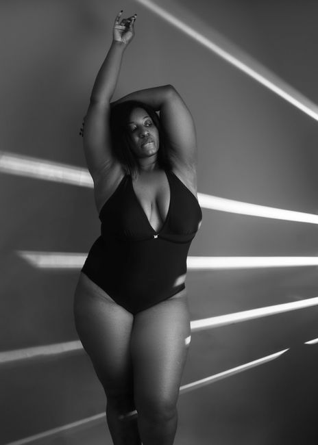 Graceful black and white portrait of a woman in stylish swimwear posing with confidence indoors.