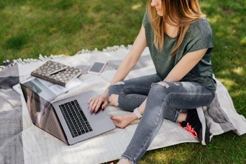 Free Student doing home assignments on laptop while sitting in park Stock Photo
