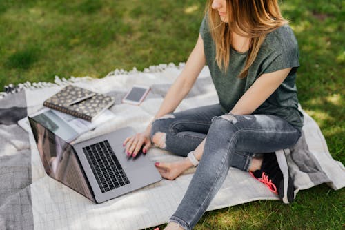 Student doing home assignments on laptop while sitting in park