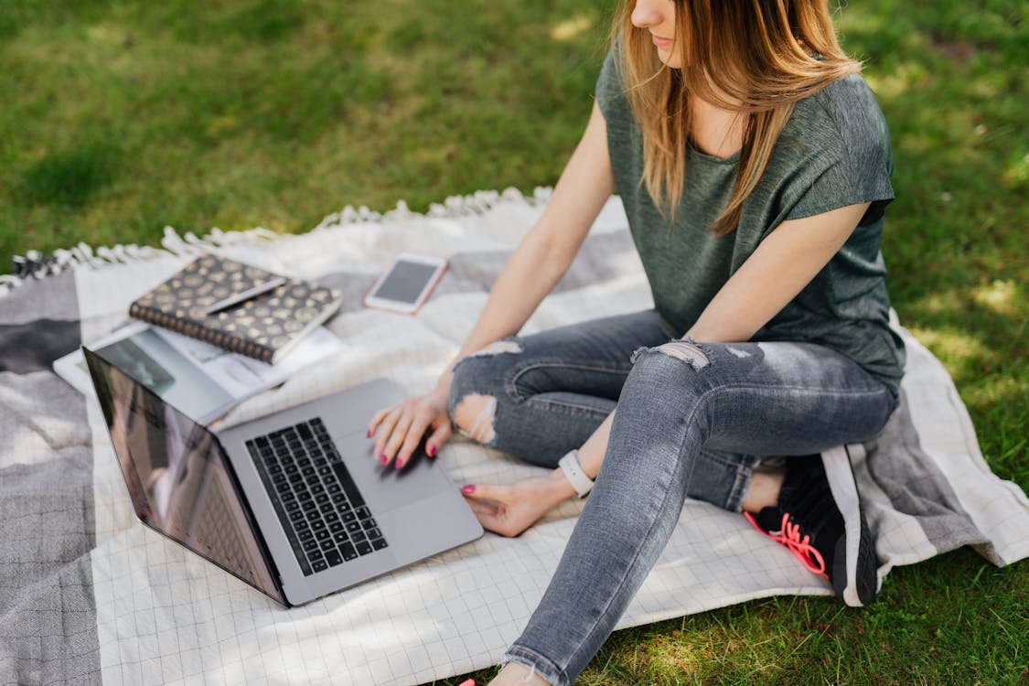 Free Student doing home assignments on laptop while sitting in park Stock Photo