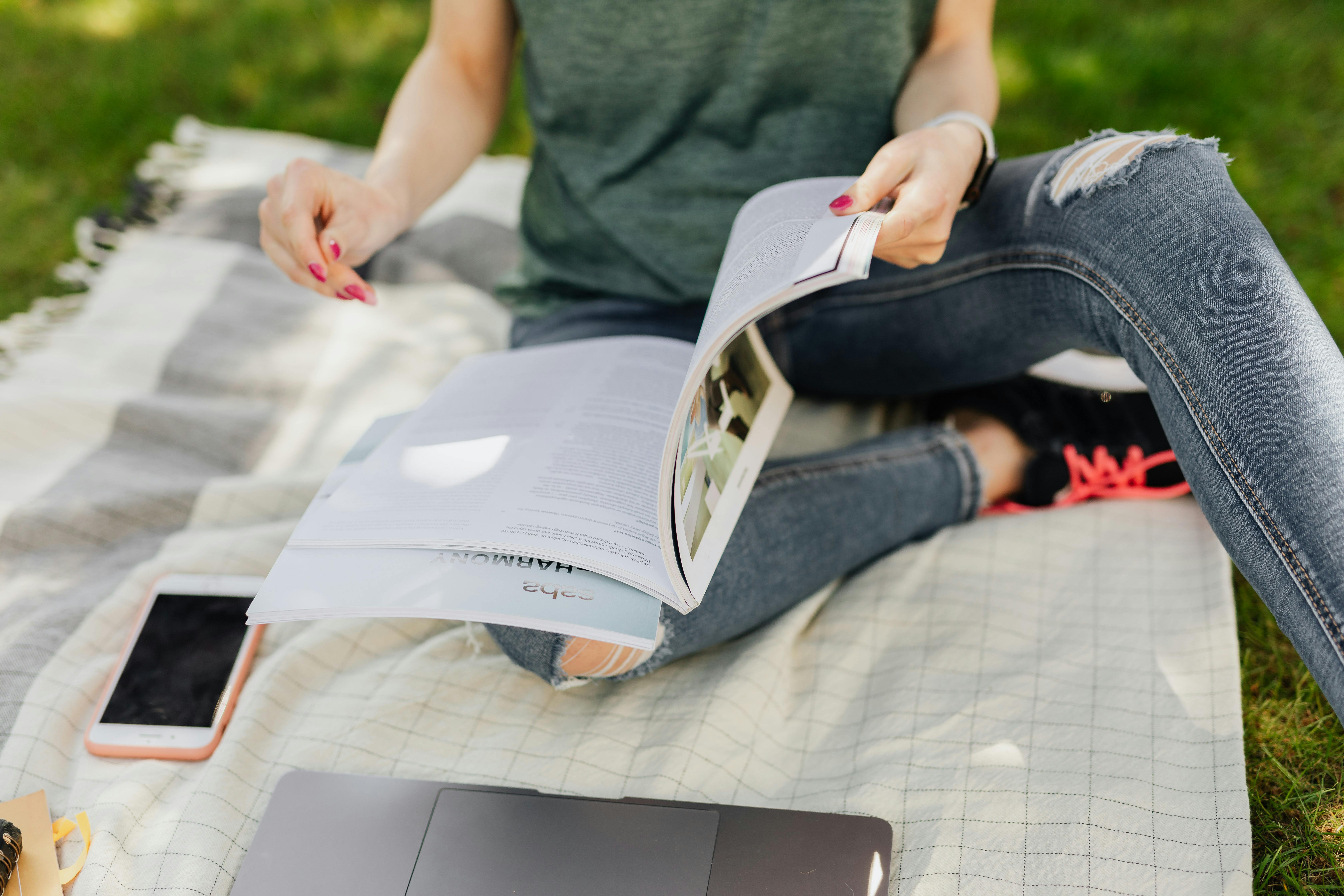 anonymous student reading textbook in quiet green park