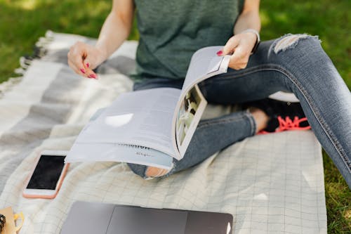 Free Anonymous student reading textbook in quiet green park Stock Photo