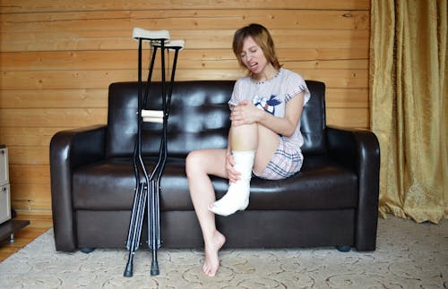 Young woman holding broken leg in cast