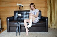 Young woman holding broken leg in cast