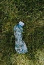 Crumpled plastic bottle on green lawn