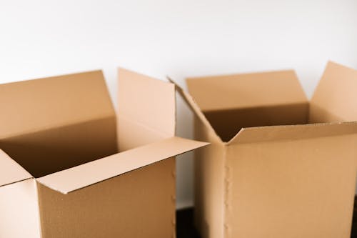 Free Opened carton boxes placed on dark surface against white plain wall in daylight before moving out Stock Photo