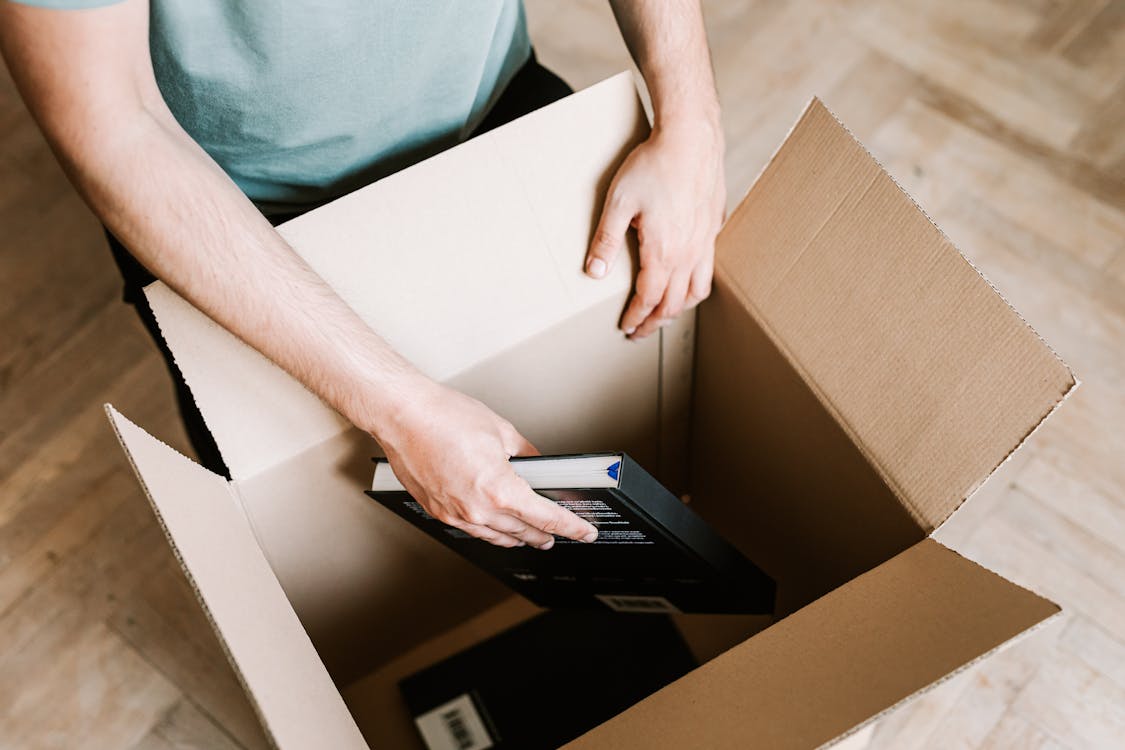 Free Crop man packing books in carton box Stock Photo