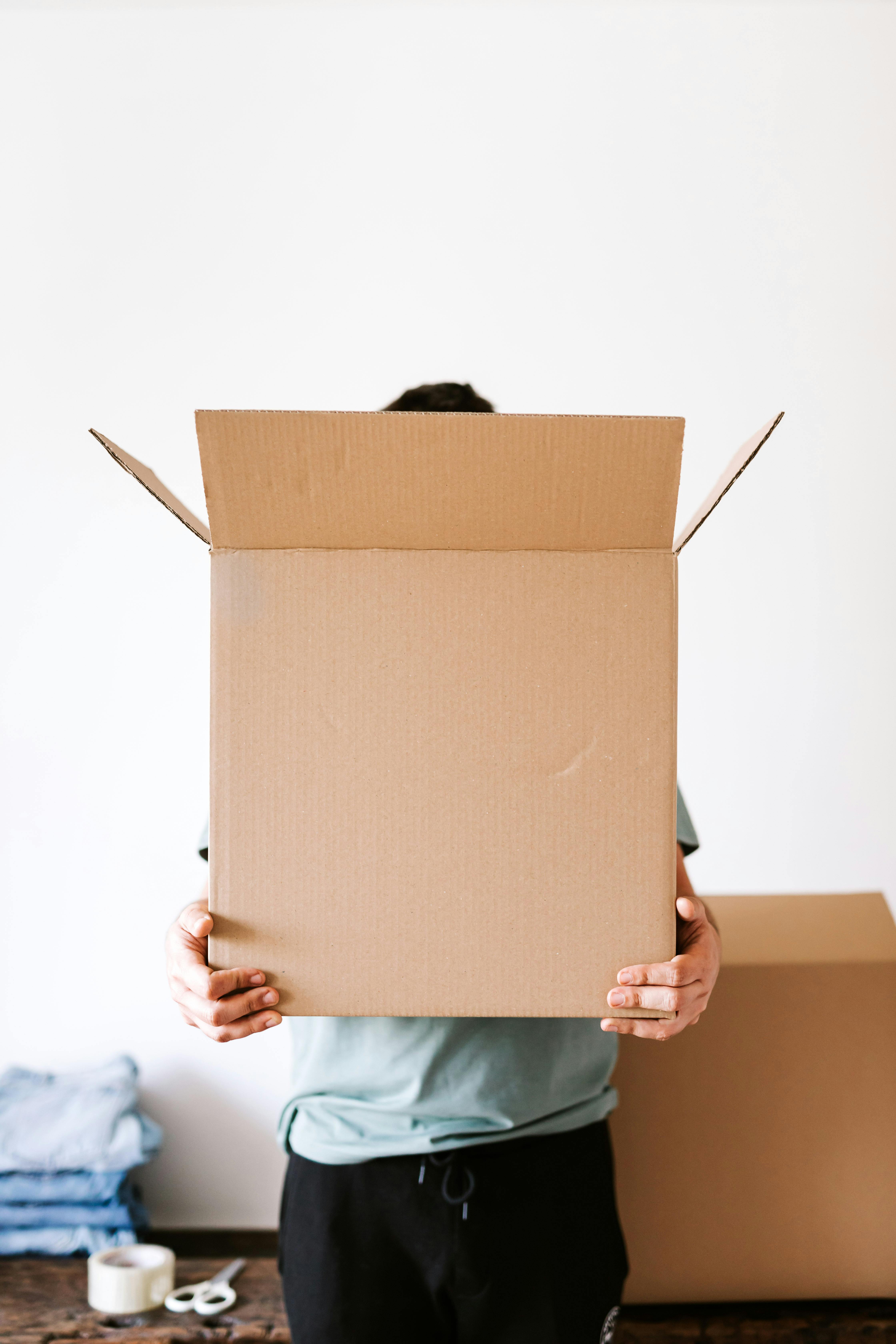 Unrecognizable man with carton box in apartment · Free Stock Photo