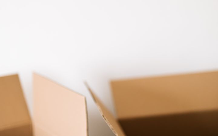 Opened carton containers placed on dark floor against white wall during renovation in daytime