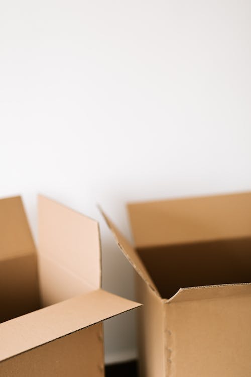 Opened carton containers placed on dark floor against white wall during renovation in daytime