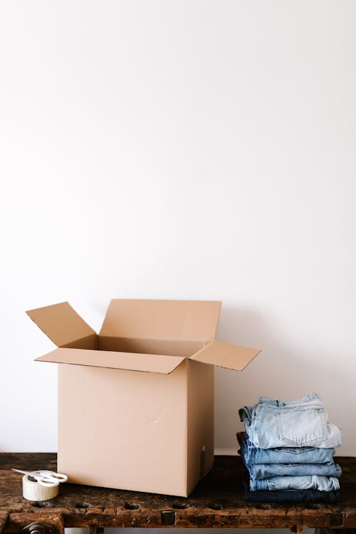 Free Carton box and stack jeans on wooden table Stock Photo
