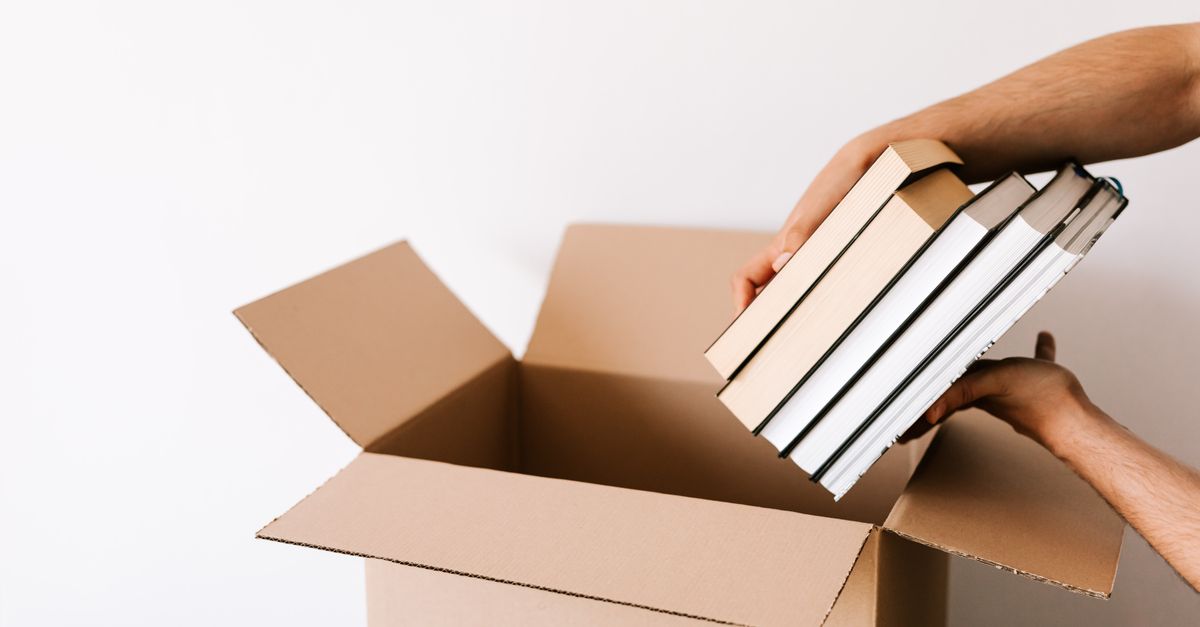 teacher packing books into box in classroom