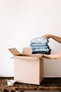 Crop person packing jeans into carton container