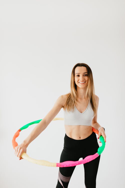 Cheerful sportswoman exercising with hula hoop