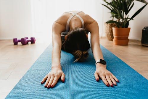 Flexible sportswoman stretching in Child Pose on mat