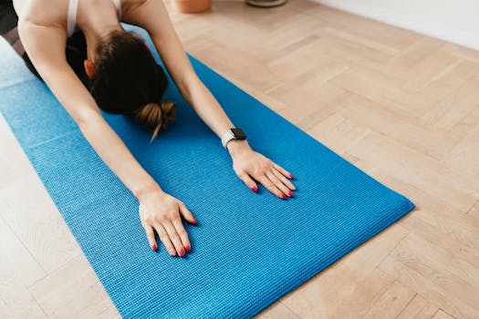 From above anonymous sporty female wearing modern smartwatch performing Child Pose during post workout stretching