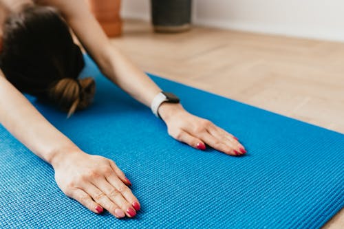 Crop anonymous woman practicing yoga on mat at home
