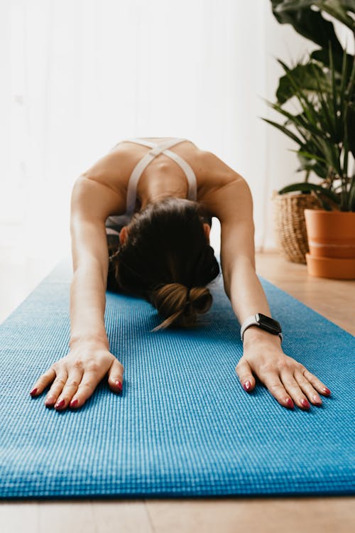 Flexible faceless woman lying in Child pose on yoga mat
