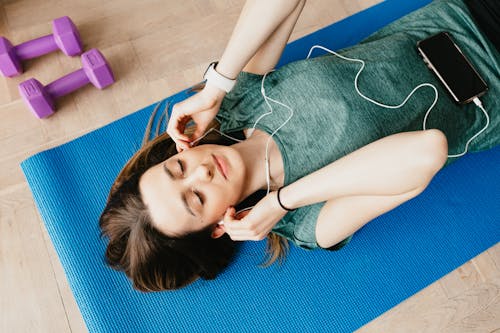 Free Sportive lady in earphones listening to music chilling on mat Stock Photo